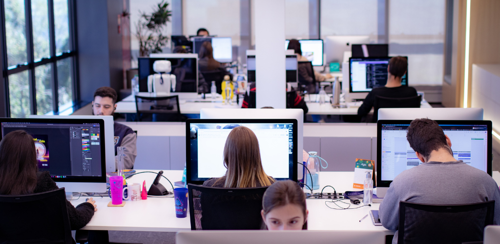 sala comercial com mesas e computadores enfileirados 